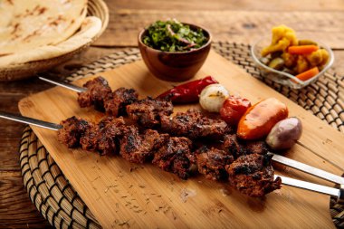 Shish Kebab or beef seekh boti served in a wooden cutting board isolated on wooden background side view