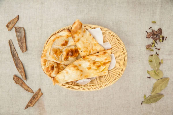 Garlic cheese naan bread served in a basket with napkin isolated on table top view of indian spices food