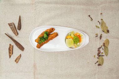 Chicken seekh Kebab with salad served in a wooden cutting board isolated on table top view of indian spices food