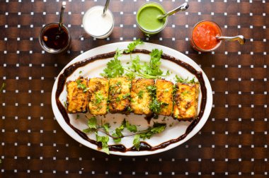paneer tikka with raita, mint, sauce, chutney and ketchup served in a dish isolated on table background top view of bangladesh food