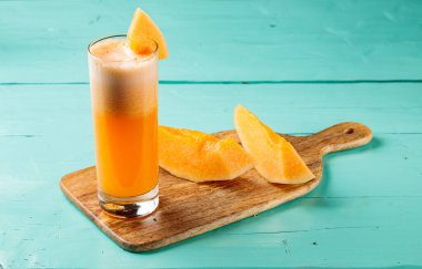 Tatlı kavun suyu çiğ karpuz ile servis edilir bir bardakta izole edilmiş kesme tahtası kenarında sağlıklı meyve suyu