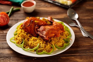 Salata ve domates soslu tavuk behari biryani ahşap masa arkasında servis edilen fast food manzaralı bir tabakta servis edilir.