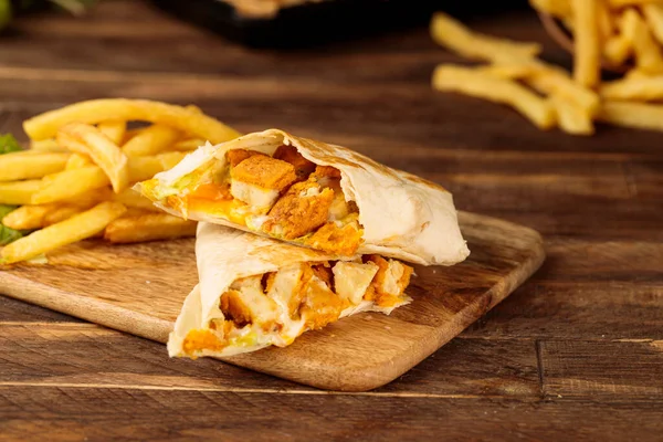 Beef Wrap shawarma with fries served in a cutting board isolated on wooden table background side view of fastfood