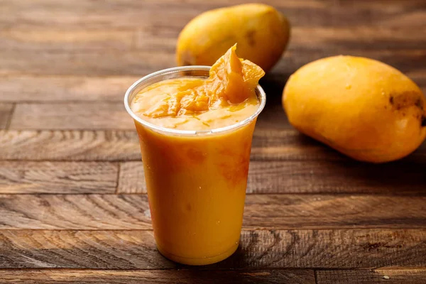 Fresh Mango Juice with mango slice served in glass side view on wooden table morning meal