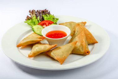 Peynirli SAMBOSA ya da soslu ve salatalı samosa gri arka planda servis edilir.