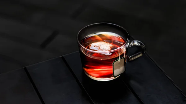 Hot Earl Grey Tea with tea bag served in a cup isolated on dark background side view