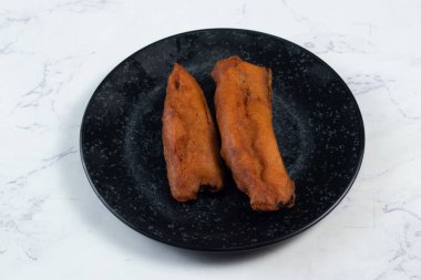 Kızarmış brinjal pakora ya da beguni, arka planda izole edilmiş Hint ve Bengali yemeklerini arka planda izole edilmiş bir tabakta servis eder. Fast fooddeep brinjal pakora veya beguni 'nin arka planda izole edilmiş bir tabakta servis edilir.