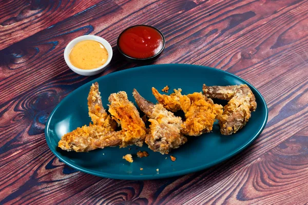 Crispy chicken wings with tomato sauce and mayo dip isolated on cutting board side view of fastfood