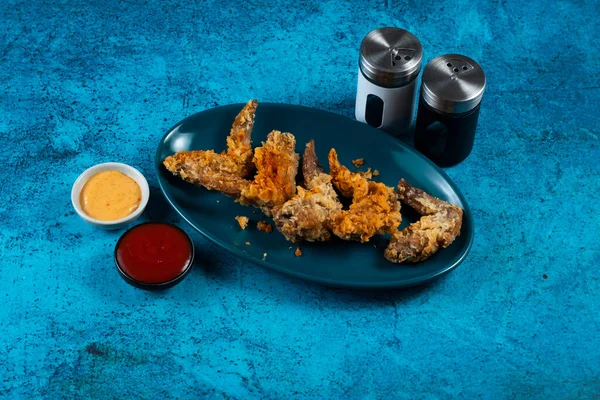 Crispy chicken wings with tomato sauce and mayo dip isolated on cutting board side view of fastfood