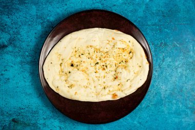 Roghni naan, khamiri roti, kulcha, ekmek veya chappati arka planda izole edilmiş bir tabakta servis edilir.