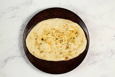 Roghni naan, khamiri roti, kulcha, ekmek veya chappati arka planda izole edilmiş bir tabakta servis edilir.
