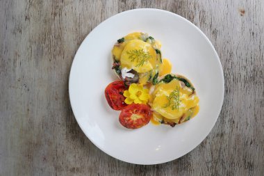 Yumurtalı Benedict pastırmalı pastırmalı pastırma, ahşap arka planda, kahvaltı manzarasında servis edilir.