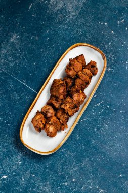 Baharatlı bbq tavuklu tikka boti kebap arka planda izole edilmiş bir tabakta servis edilir.