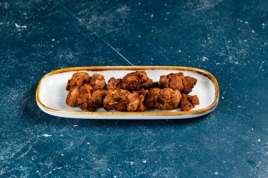 Baharatlı bbq tavuklu tikka boti kebap arka planda izole edilmiş bir tabakta servis edilir.