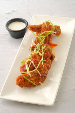 Fast food 'un sarı arka planında izole edilmiş bir tabakta servis edilen tavuk bufalo kanatları.