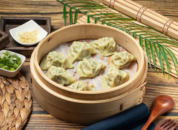 Steamed dumplings with green onion and meat with wood spoon and napkin served in a wooden dish side view of taiwan food