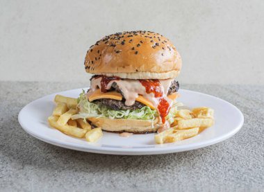 Fast food 'un gri arka planında izole edilmiş bir tabakta servis edilen klasik etli burger.