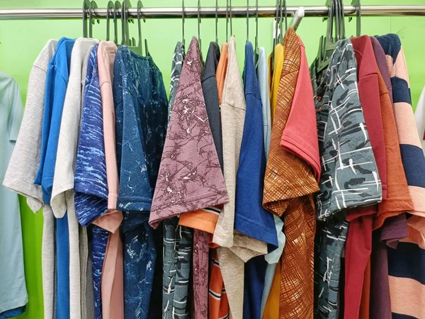 colorful men t shirt clothes on hangers in shop