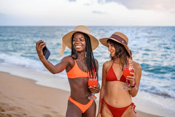 Радостные подружки со смартфоном делают селфи на пляже — стоковое фото