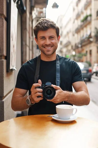 길거리 카페에서 사진기로 사진을 찍고 있는 미소짓는 남자 — 스톡 사진