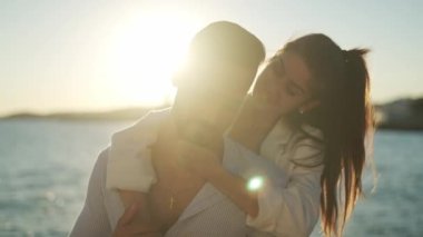 Parlak denize karşı kucaklaşan gülümseyen etnik çift