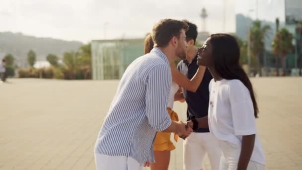 Cuatro amigos multirraciales felices positivos abrazándose y besándose durante la reunión al aire libre en verano — Vídeo de stock