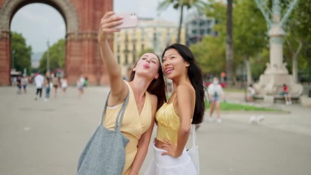 Zwei lächelnde Freundinnen blicken auf Smartphone-Bildschirm und machen Selfie-Porträt — Stockvideo