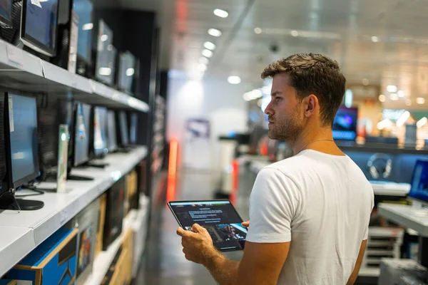 Человек с планшетом во время покупок в магазине электроники — стоковое фото