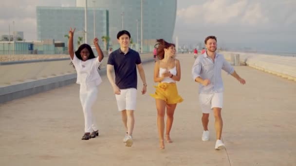 Jóvenes de raza mixta felices saltando, corriendo felices afuera juntos en el cálido día de verano — Vídeos de Stock