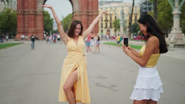Genç bayan turist zafer kemerine karşı poz verirken bayan arkadaşı film çekiyor. — Stok video