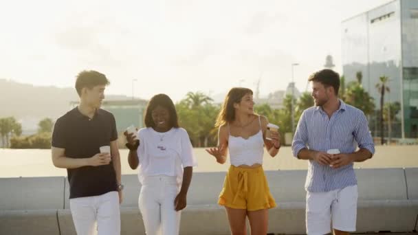 Négy fiatal, mosolygós, többnemzetiségű barát ivott. Elvitték a kávét és beszélgettek a szabadban. — Stock videók