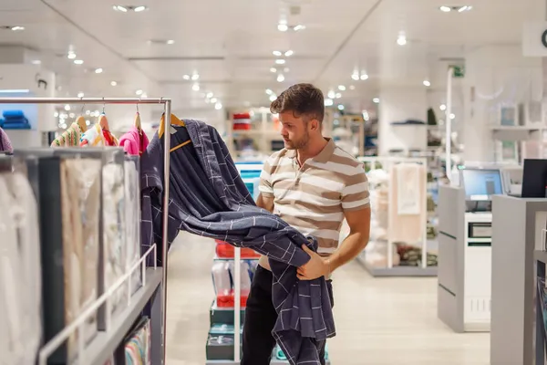 Homem comprando roupão de banho na loja moderna — Fotografia de Stock