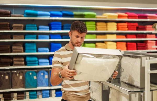 Homem selecionando roupas de cama na loja — Fotografia de Stock