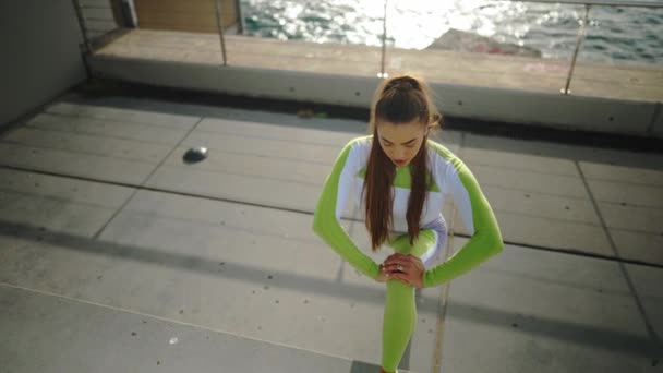 Unga idrottskvinna värmer upp på banvallen — Stockvideo