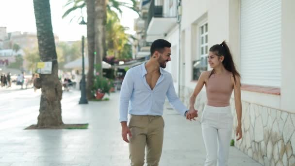 Leende latinamerikanskt par som håller varandra i handen medan de pratar på gatan — Stockvideo