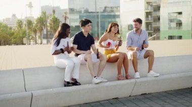 Farklı ırklardan mutlu arkadaşlar dışarıda taşınabilir kablosuz bluetooth hoparlöründen müzik dinliyorlar.