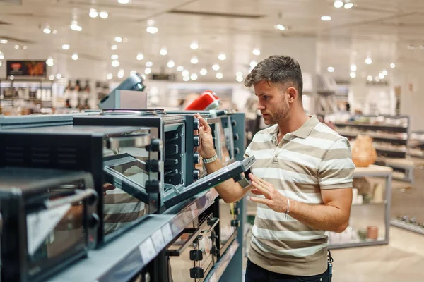 Hombre mirando dentro del horno de microondas en la tienda — Foto de Stock