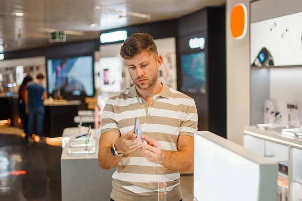 Человек осматривает смартфон в технологическом магазине — стоковое фото