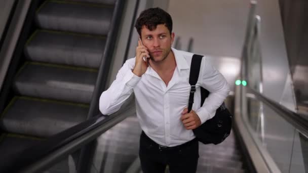 Бізнесмен розмовляє по смартфону на ескалаторі — стокове відео