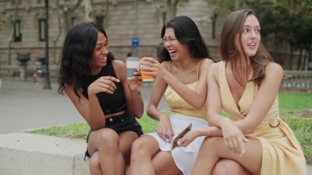 Três felizes namoradas mestiças felizes bebendo levam café e rindo ao ar livre — Vídeo de Stock