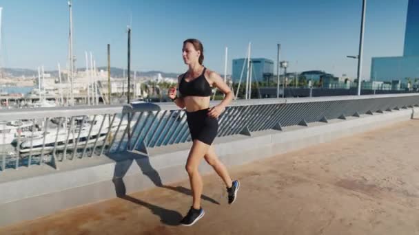 朝に港近くをジョギングするスポーツ女性 — ストック動画