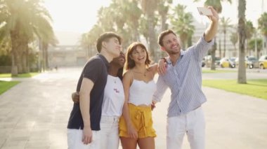 Neşeli çok ırklı arkadaşlar yaz tatillerini birlikte deniz kıyısında geçirirken selfie çekiyorlar.