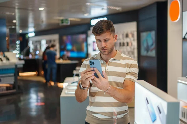 Мужской клиент использует мобильный телефон перед покупкой — стоковое фото