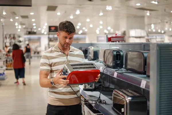 Alışveriş merkezinde ekmek kızartma makinesi seçen adam — Stok fotoğraf