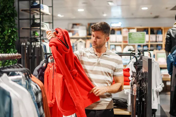 Homem escolhendo capuz na loja — Fotografia de Stock