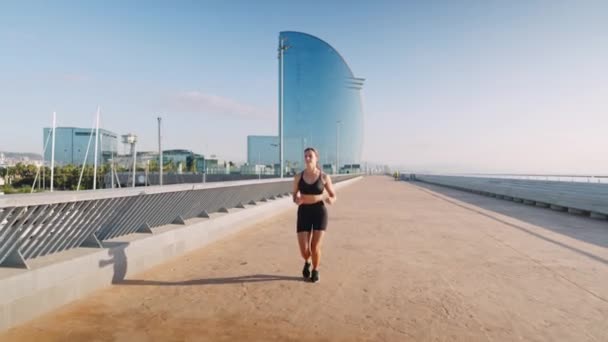 Sportvrouw loopt op dijk in de ochtend — Stockvideo