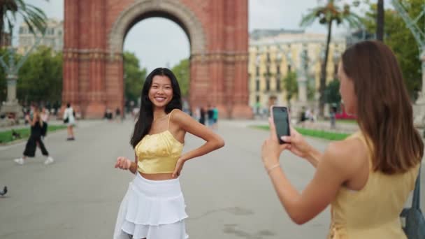 Vrouw fotograferen haar prachtig beste vrouwelijke vriend van aziatische etniciteit met mobiele telefoon buiten — Stockvideo