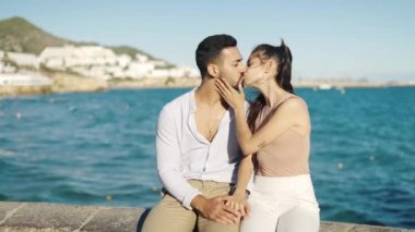 Tebessüm eden İspanyol çift sette öpüşürken konuşuyor.