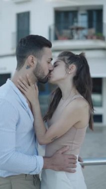 Gülümseyen İspanyol çift sokakta konuşuyor ve öpüşüyor.