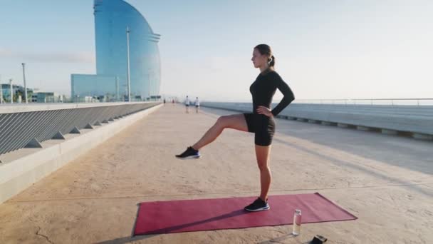 Sportvrouw doet evenwichtsoefening op dijk — Stockvideo